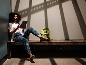 Person using a tablet while seated on an indoor bench