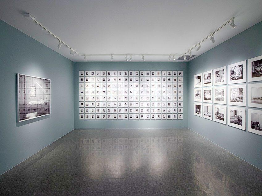 Photograph of the gallery space at CVA. It is a small square room with light turquoise walls and framed black and white photographs hung on the walls. The photographs are of beds and sleeping places.